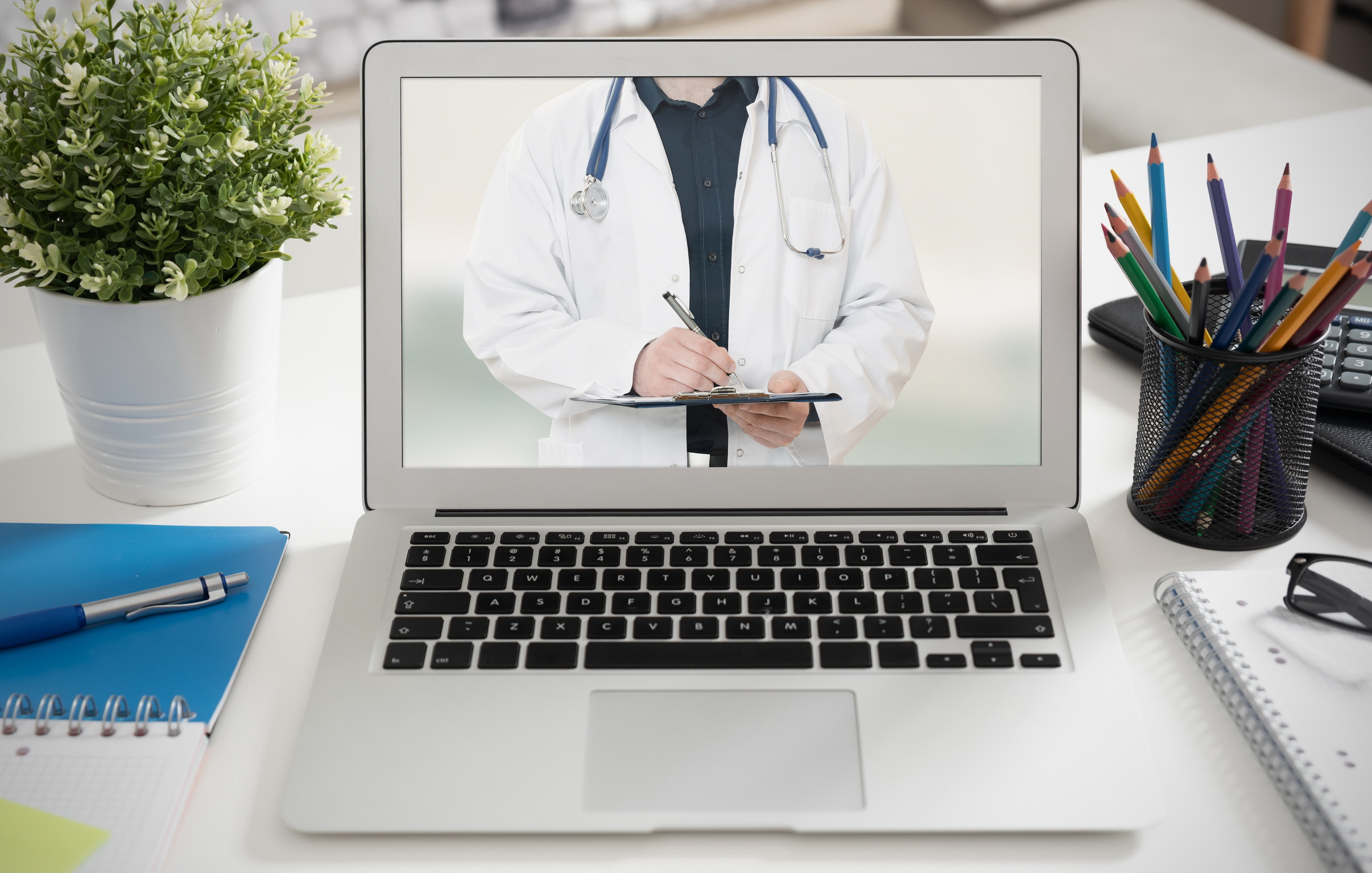 Im Display des Laptops ist ein Arzt / eine Ärztin zu sehen