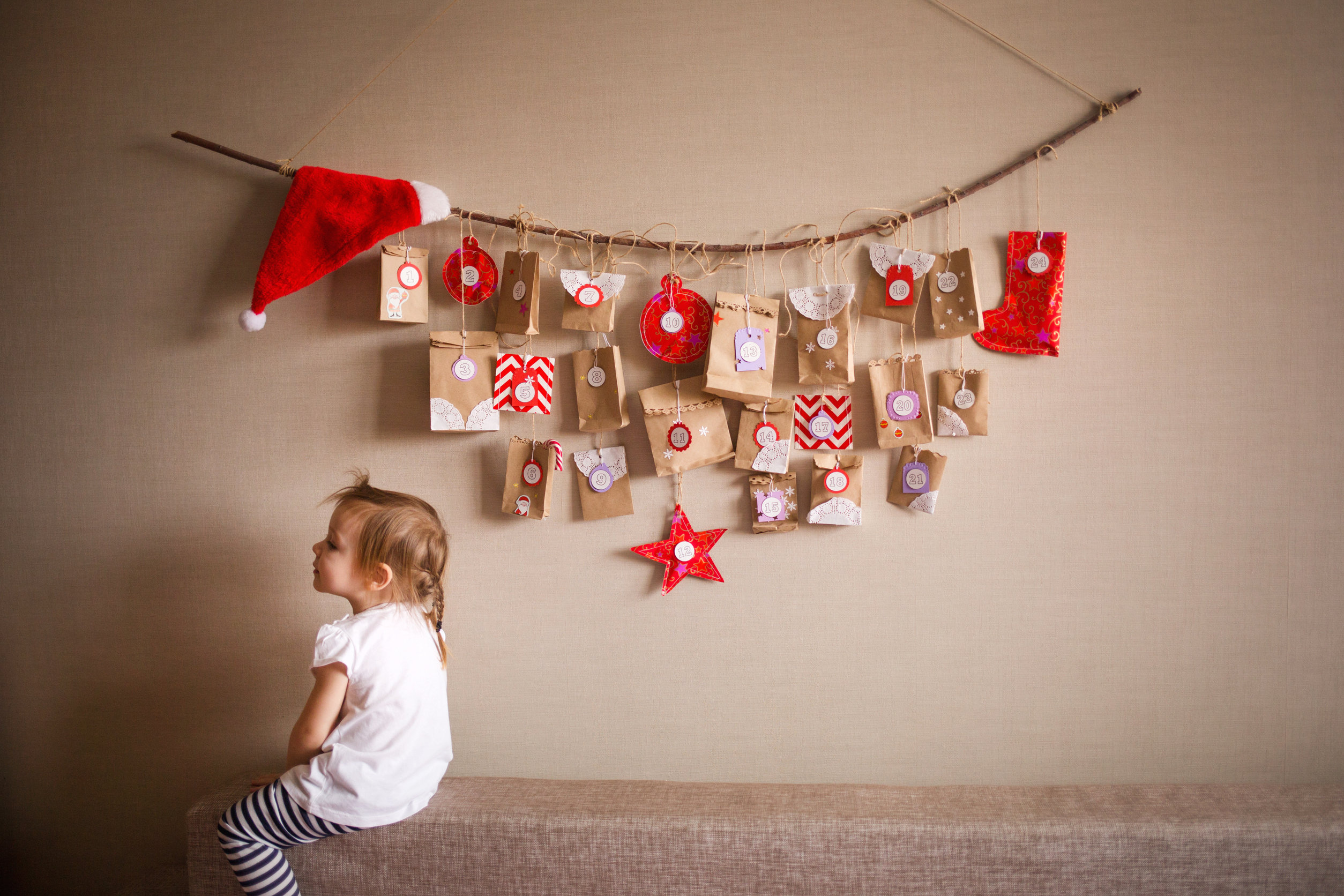 Leider haben wir keinen Titel zu diesem Bild. Wir arbeiten daran und bitten um Ihr Verständnis. Kind sitzt auf einer Bank vor einem Adventskalender