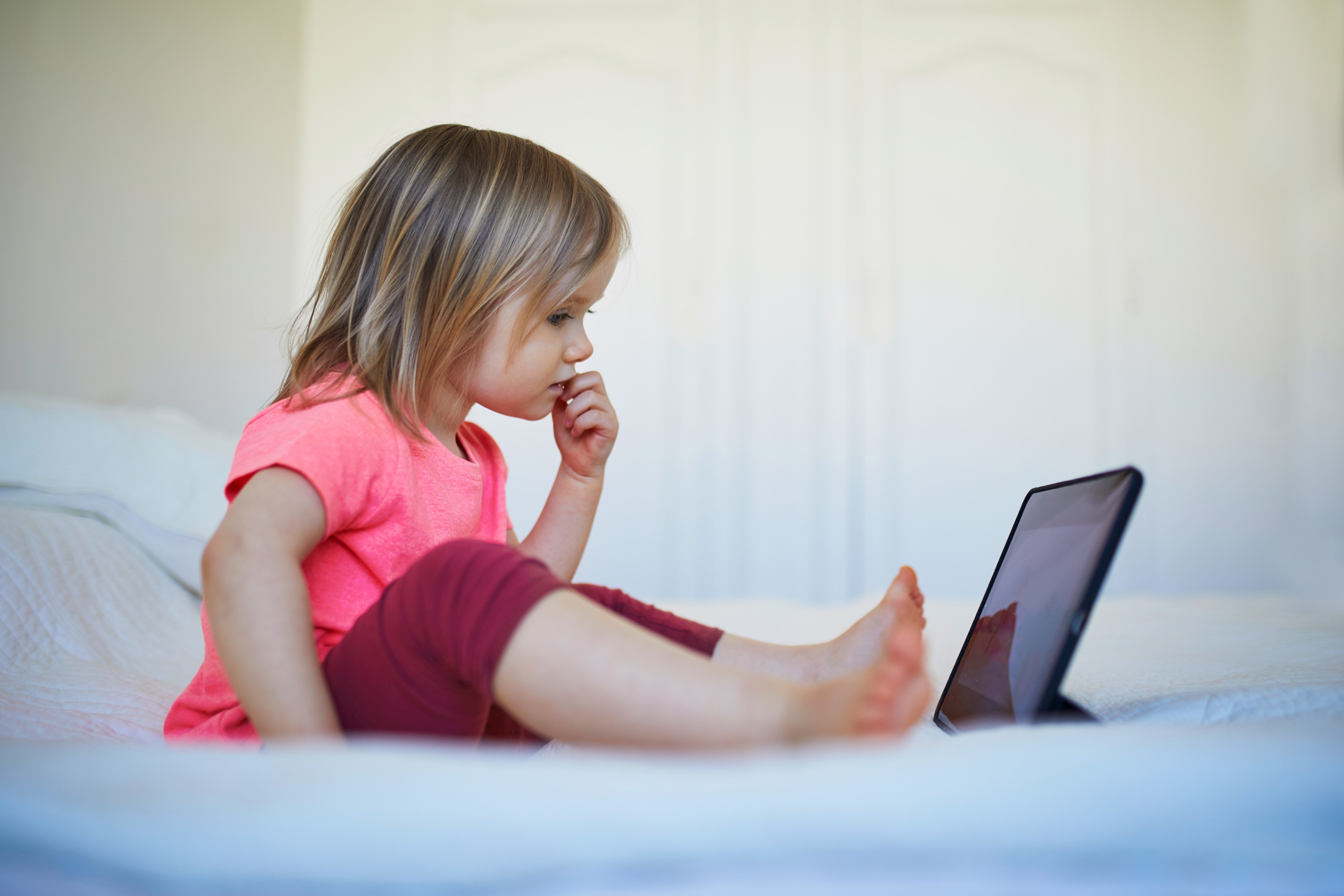 Kleines Mädchen sitzt alleine vor einem Tablet